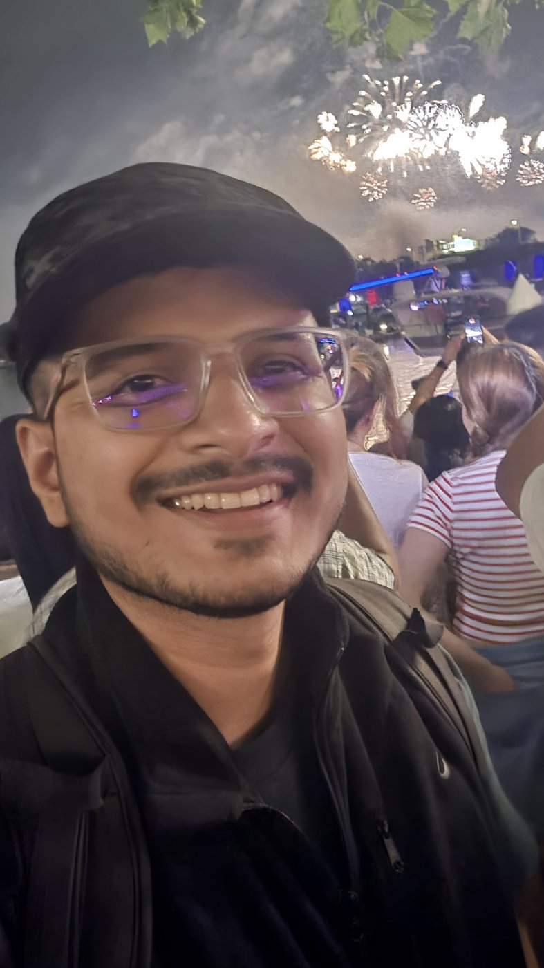 A selfie in the Fourth of July crowd with fireworks bursting over the water behind